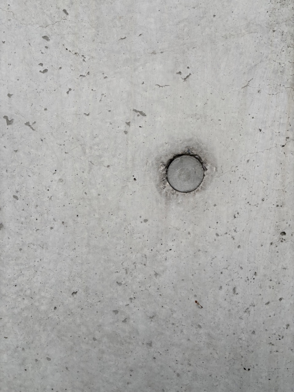 Photograph of concrete wall with circular cut out, rough surface